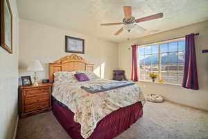 Carpeted bedroom featuring a mountain view, ceiling fan, and a textured ceiling