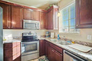 Kitchen featuring appliances with stainless steel finishes, decorative light fixtures, light tile patterned floors, and sink