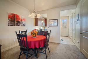 Dining room featuring light carpet, ornamental molding, a textured ceiling, and an inviting chandelier