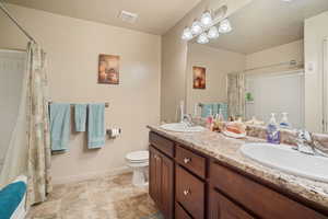 Full bathroom featuring a textured ceiling, vanity, toilet, and shower / bathtub combination with curtain