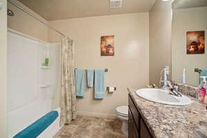 Full bathroom featuring shower / tub combo, vanity, a textured ceiling, and toilet