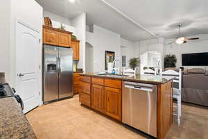 Kitchen featuring ceiling fan, sink, stainless steel appliances, an island with sink, and light tile patterned floors