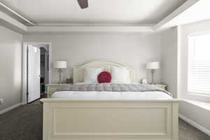 Bedroom featuring dark colored carpet, a raised ceiling, and ceiling fan