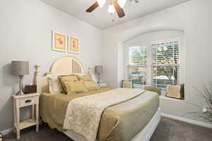 Bedroom with ceiling fan and dark carpet