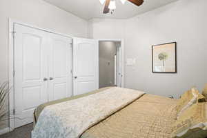 Bedroom with ceiling fan, a closet, and carpet floors