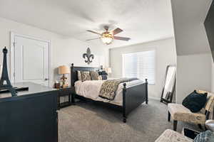 Carpeted bedroom featuring ceiling fan and a textured ceiling