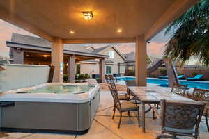 Patio terrace at dusk with a swimming pool with hot tub