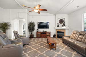 Living room featuring ceiling fan, lofted ceiling, and a tiled fireplace