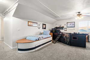 Carpeted bedroom featuring a textured ceiling, ceiling fan, and vaulted ceiling