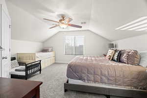 Carpeted bedroom featuring ceiling fan and lofted ceiling