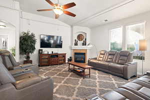 Living room with ceiling fan, a tile fireplace, and vaulted ceiling