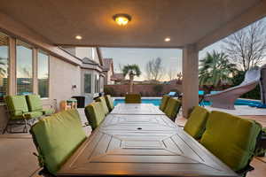 Patio terrace at dusk with a fenced in pool