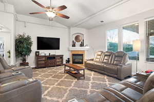 Living room with a tile fireplace, ceiling fan, and lofted ceiling