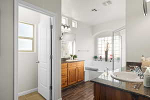 Bathroom with wood-type flooring, vanity, and a tub to relax in