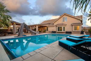 Pool at dusk with a patio area and a water slide