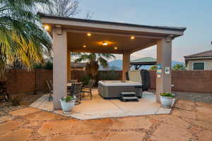 Patio terrace at dusk featuring a gazebo and a hot tub