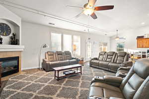 Living room with hardwood / wood-style flooring, ceiling fan, lofted ceiling, and a tiled fireplace