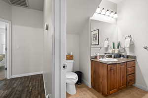 Bathroom with vanity, toilet, and vaulted ceiling