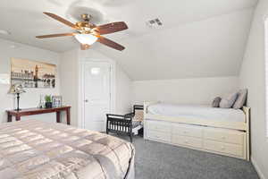 Carpeted bedroom with ceiling fan and lofted ceiling