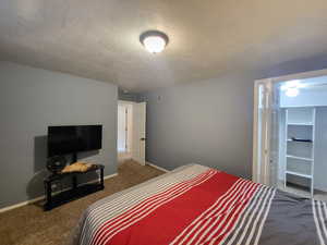 Bedroom featuring dark colored carpet and a textured ceiling