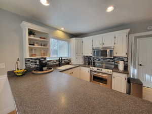 Kitchen featuring white cabinets, backsplash, sink, and stainless steel appliances