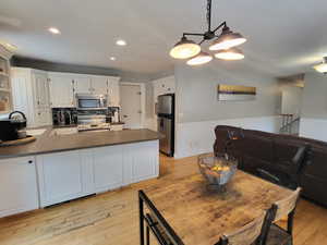 Kitchen with white cabinets, sink, kitchen peninsula, stainless steel appliances, and a chandelier