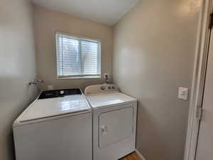 Laundry room with light hardwood / wood-style flooring and washing machine and clothes dryer