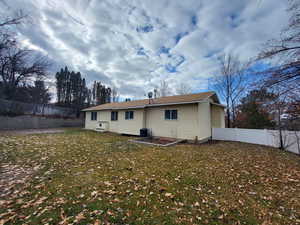 Back of house featuring central air condition unit and a lawn