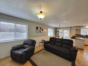 Living room featuring a chandelier, a textured ceiling, light wood flooring