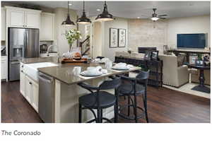 Kitchen with a tile fireplace, ceiling fan, a kitchen island with sink, white cabinets, and appliances with stainless steel finishes