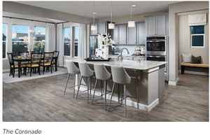 Kitchen featuring stainless steel appliances, hanging light fixtures, a breakfast bar area, and an island with sink