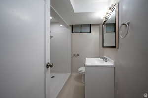 Bathroom featuring walk in shower, vanity, a textured ceiling, and toilet