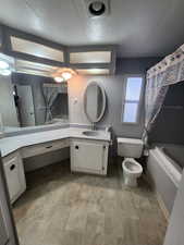 Full bathroom with shower / tub combo with curtain, vanity, a textured ceiling, and toilet