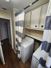 Laundry area featuring cabinets, dark hardwood / wood-style flooring, and washer / dryer