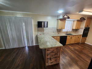 Kitchen with light stone countertops, tasteful backsplash, dark wood-type flooring, sink, and black appliances