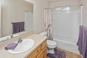 Full bathroom with tile patterned flooring, vanity, shower / bath combination with curtain, and toilet