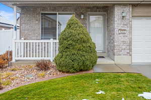 Doorway to property with covered porch and a garage