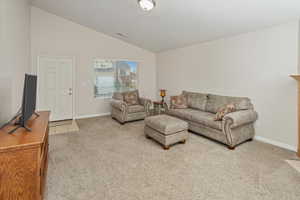 Carpeted living room with vaulted ceiling