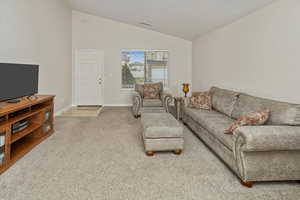 Carpeted living room featuring lofted ceiling