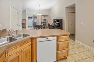 Kitchen with white dishwasher, sink, light tile patterned floors, a notable chandelier, and hanging light fixtures