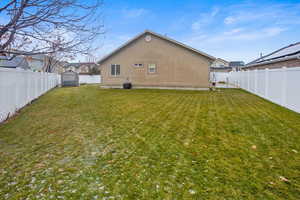 Back of property with a storage unit and a yard