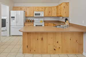 Kitchen with kitchen peninsula, white appliances, and sink