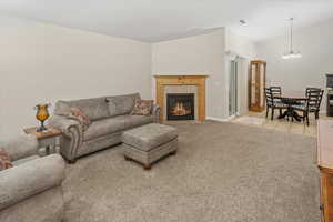 Living room with a fireplace, light carpet, and a chandelier