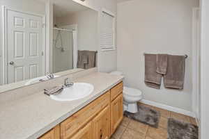 Bathroom with tile patterned floors, vanity, toilet, and walk in shower