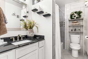 Full bathroom with tile patterned flooring, vanity, toilet, and shower / tub combo with curtain