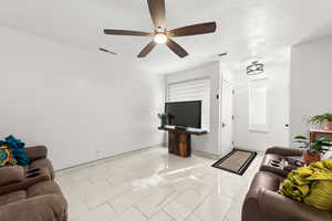 Living room featuring ceiling fan and a textured ceiling