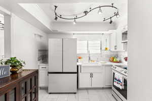 Kitchen featuring white cabinets, sink, white fridge, and electric range oven