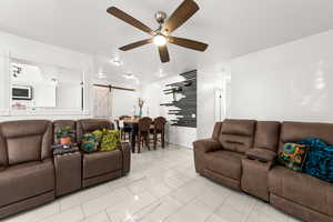 Living room with ceiling fan and a barn door