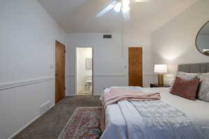 Carpeted bedroom with connected bathroom and ceiling fan