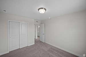 Unfurnished bedroom with light carpet and a closet